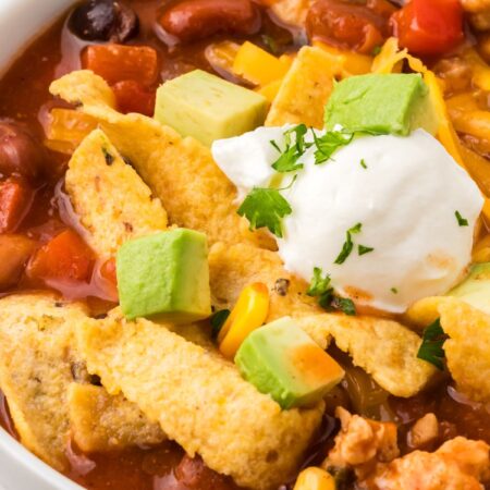 A white bowl of turkey taco soup with toppings for serving.
