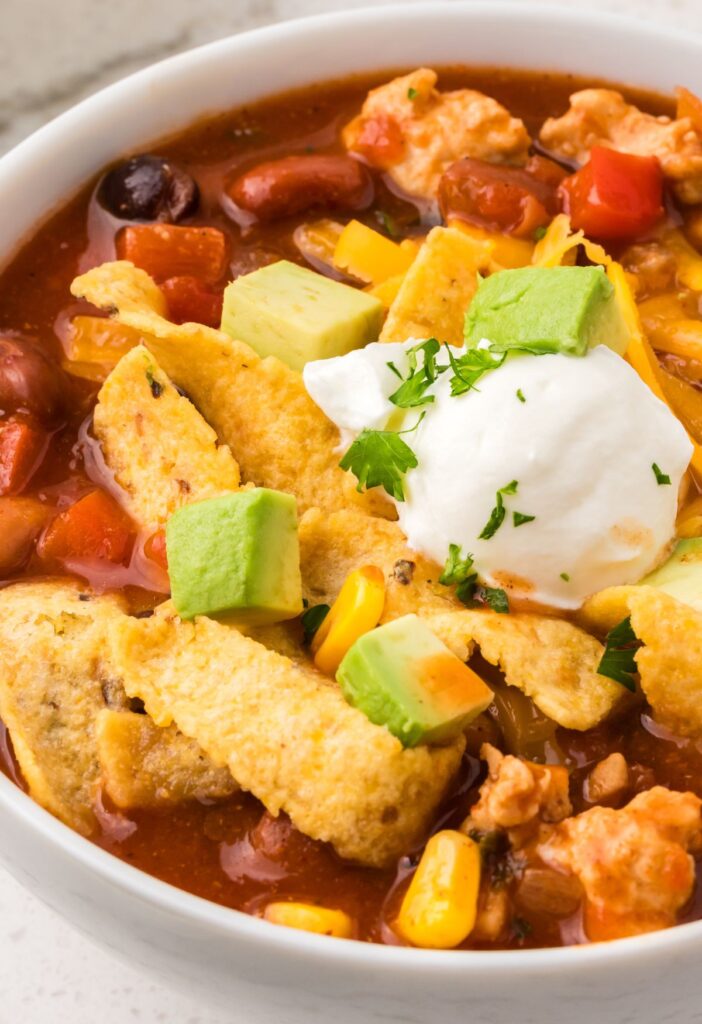 A white bowl of turkey taco soup with toppings for serving.