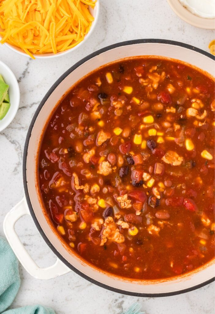 Pot of the turkey chili taco soup with bowls of toppings around it.
