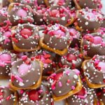 Valentines Day treat recipe of caramel pretzel bites with a pink m&m and sprinkles.