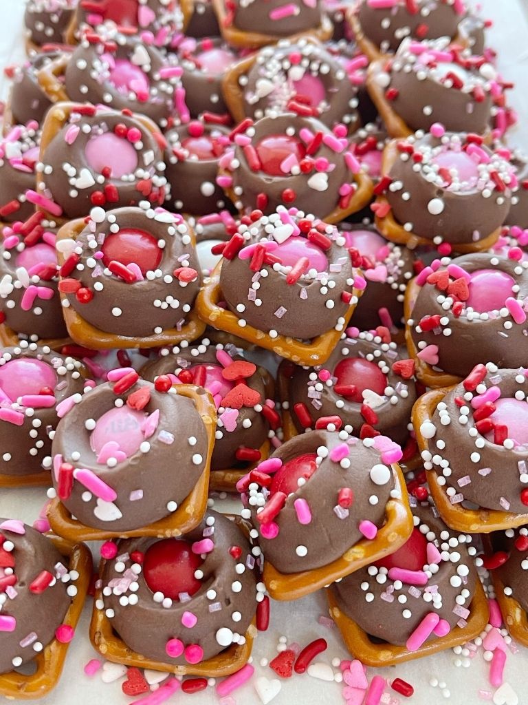 Valentines Day treat recipe of caramel pretzel bites with a pink m&m and sprinkles. 