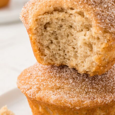Stack of two muffins with the top having a bite taken out of it to show the soft middle.
