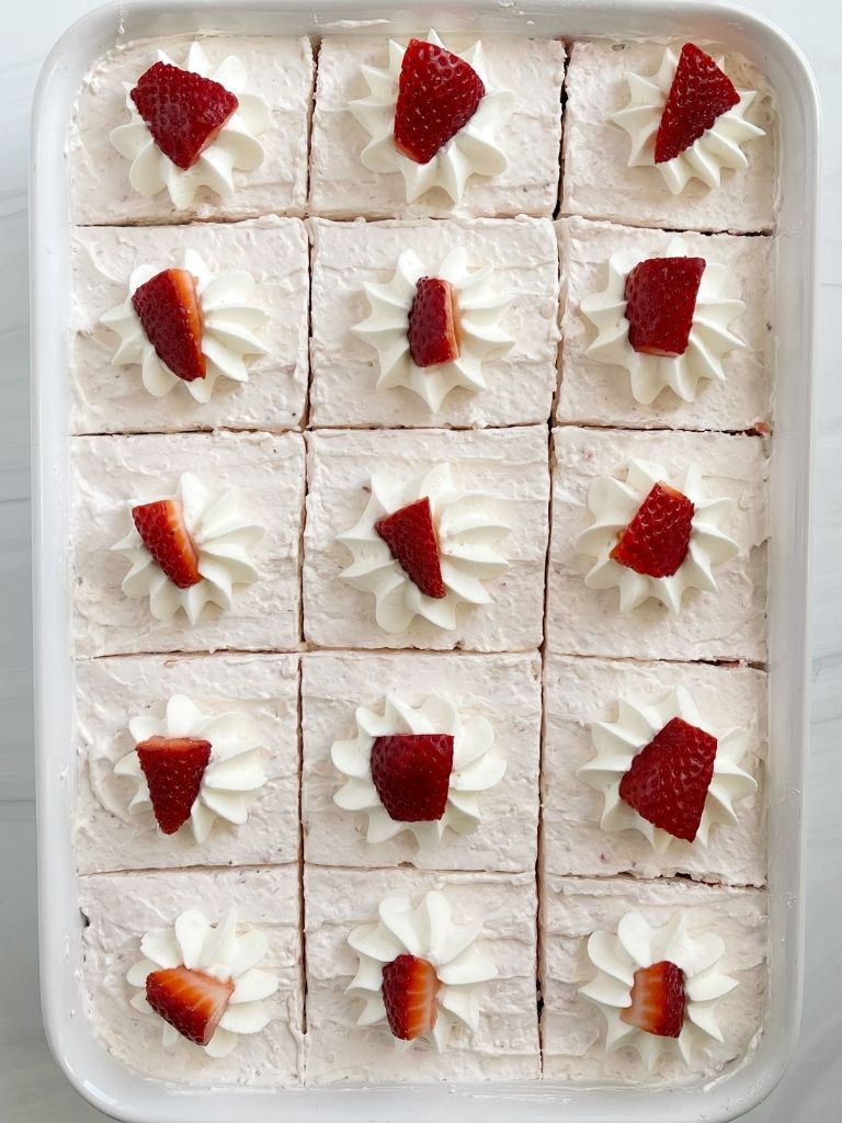 Strawberry cake recipe topped with fluffy frosting and strawberries. 