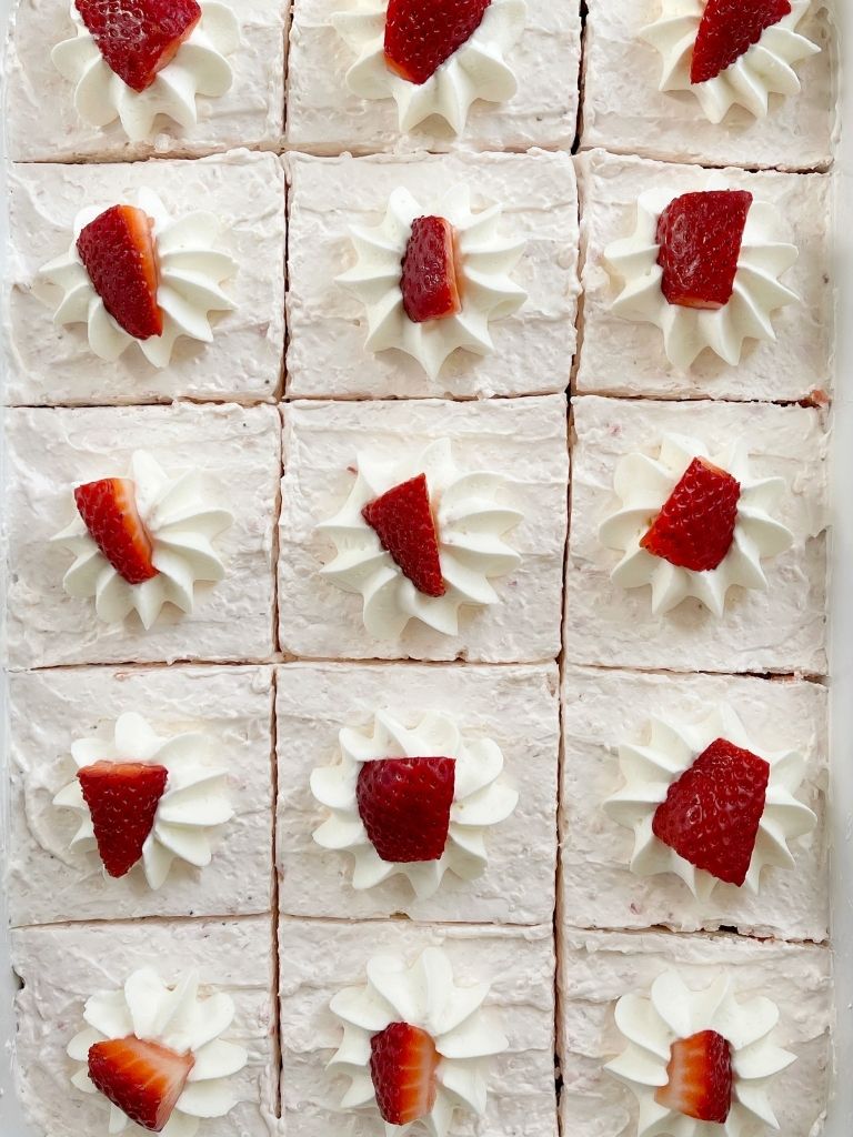 Easy strawberry cake inside a baking pan topped with whipped cream and strawberries. 