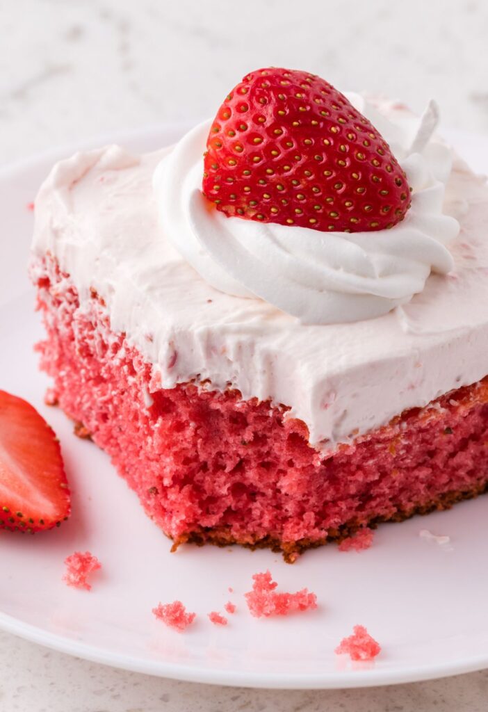 Slice of cake on a white plate with a fork bite taken out of the front corner. 