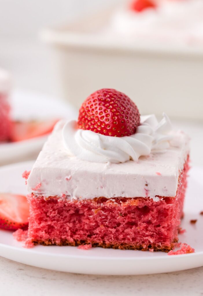 Slice of the cake on a white plate and a strawberry on top
