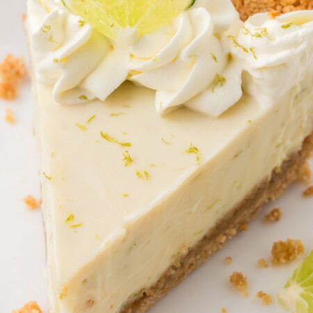 A slice of key lime pie ready to serve on a white plate.