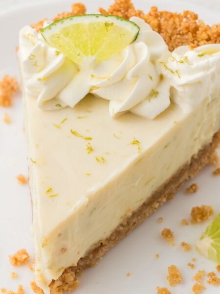 A slice of key lime pie ready to serve on a white plate.