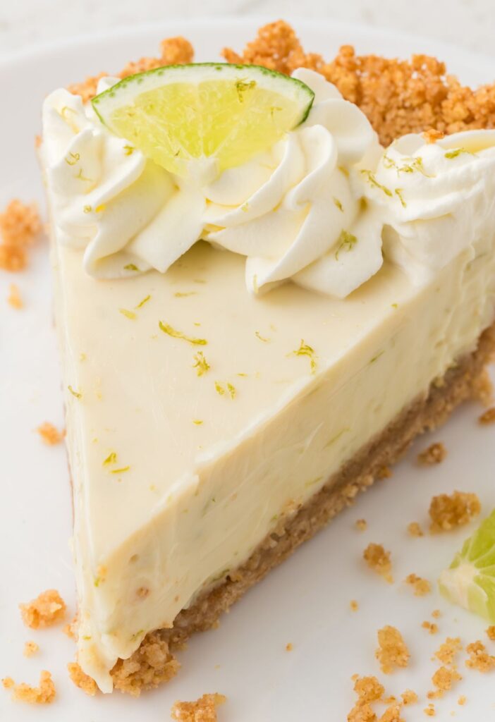 A slice of key lime pie ready to serve on a white plate.