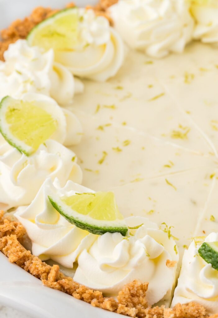 Side view of the key lime pie in a graham cracker crust and whipped cream on top.