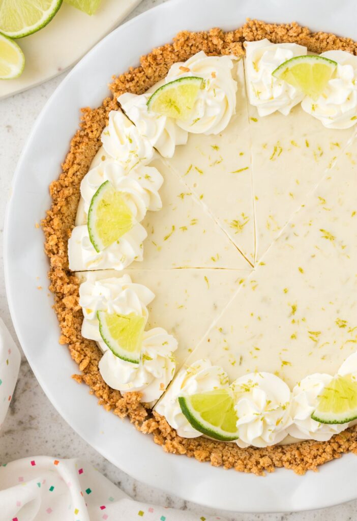 Top view of the whole key lime pie garnished with lime slices.