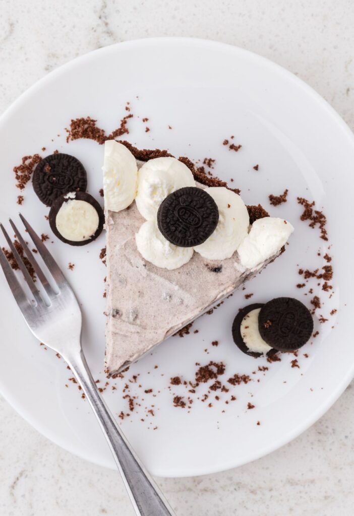 A slice of Oreo pudding pie on a white plate with a fork. 