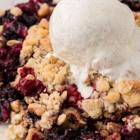 A serving of the crisp with frozen berries and ice cream on top.