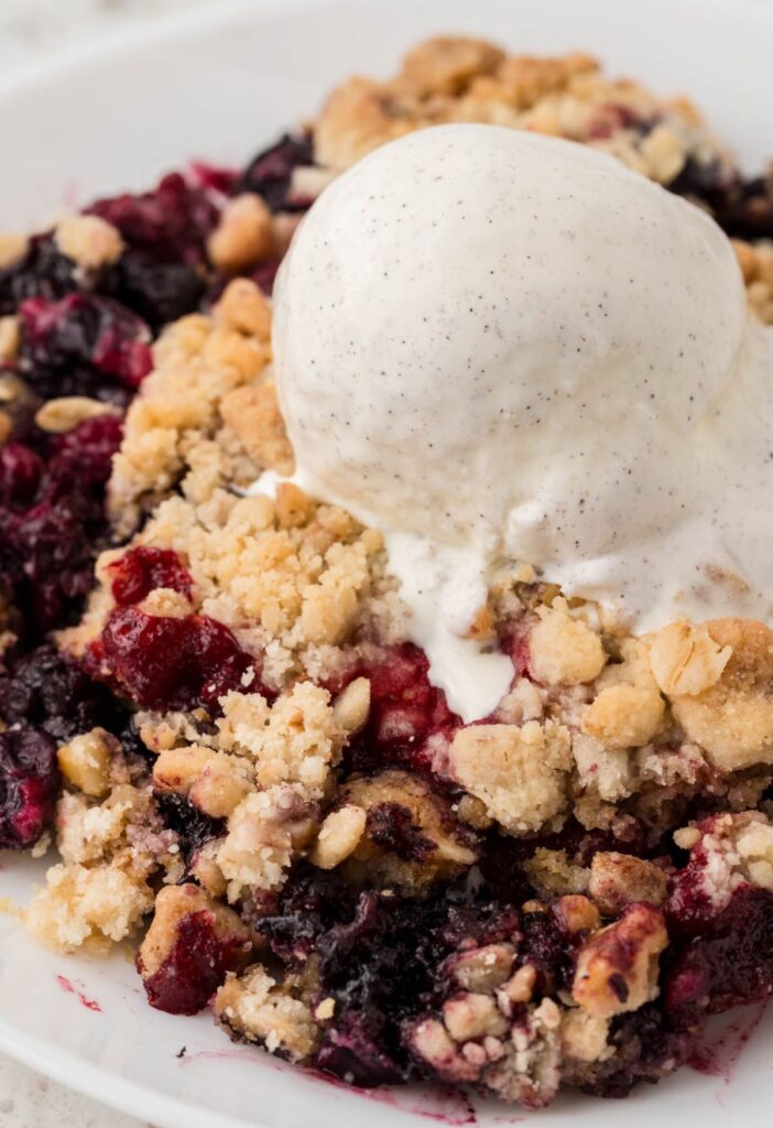 A serving of the crisp with frozen berries and ice cream on top.