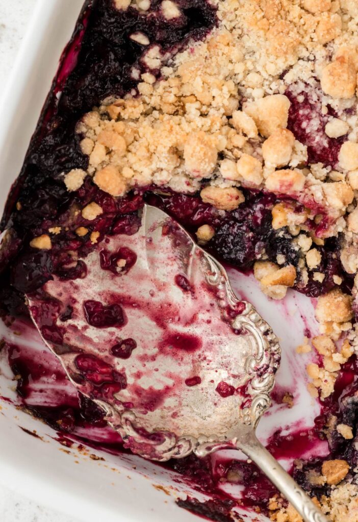 The pan of berry crisp with a serving spoon scooping some up.