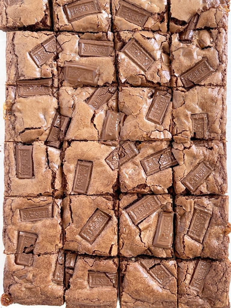 An overhead shot of a pan of brownies with Hershey chocolate bars on top. Cut into squares. 