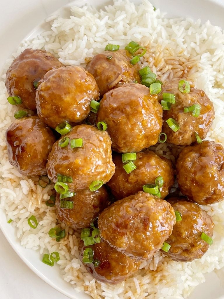 Overhead picture of turkey meatballs on top of rice on a white plate. 