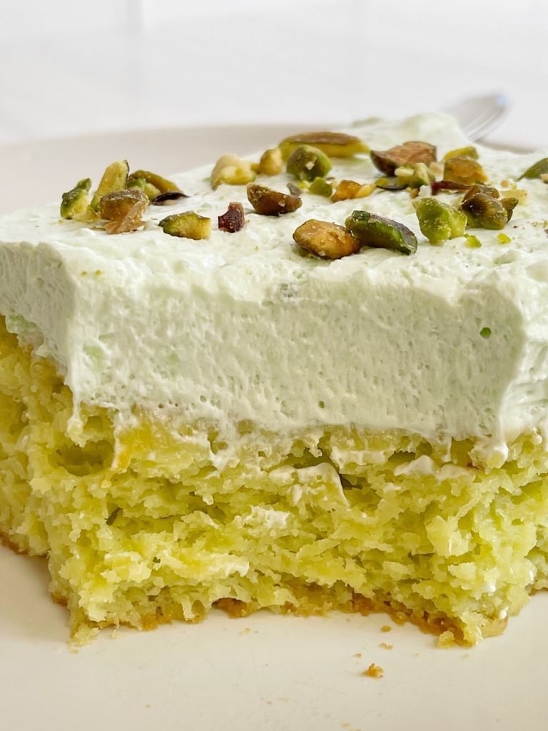 Slice of pistachio cake on a white plate.