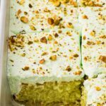Inside of the cake pan with the pineapple pistachio cake inside, baked and one slice taken out of the pan.