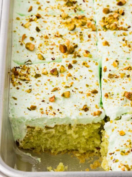 Inside of the cake pan with the pineapple pistachio cake inside, baked and one slice taken out of the pan.