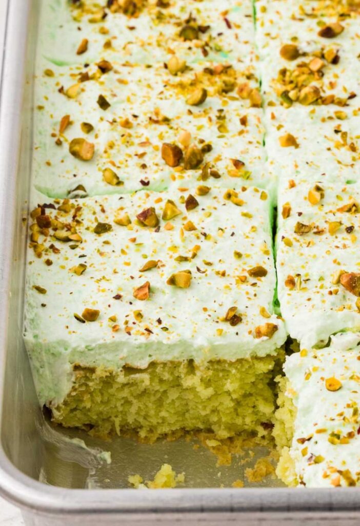 Inside of the cake pan with the pineapple pistachio cake inside, baked and one slice taken out of the pan.