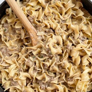 A skillet pan with beef stroganoff and a wooden spoon in it.