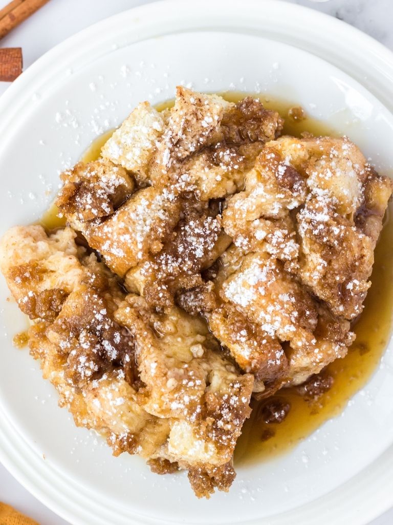 A garnished piece of casserole with French toast and powdered sugar.