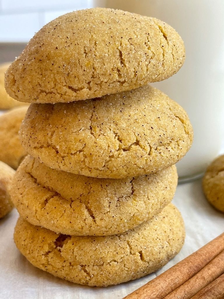 A stack of pumpkin snickerdoodle cookies with a can of milk behind it and cinnamon sticks for decorations.