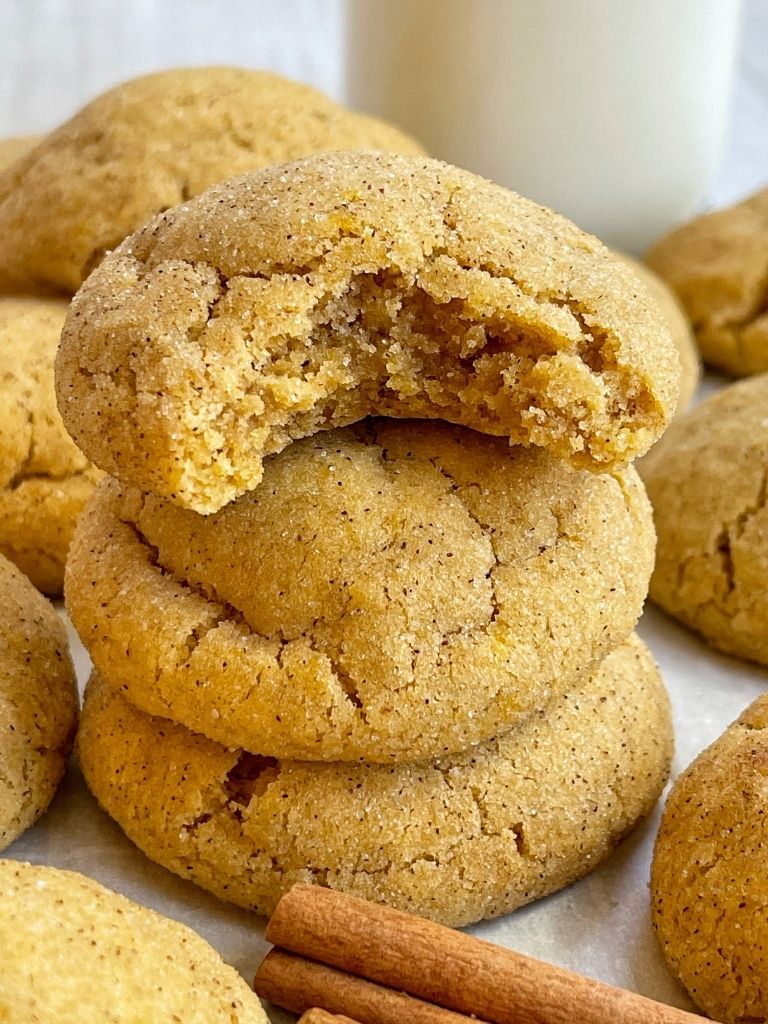 Stack of pumpkin snickerdoodle cookies with the top having a bite taken out of it. 