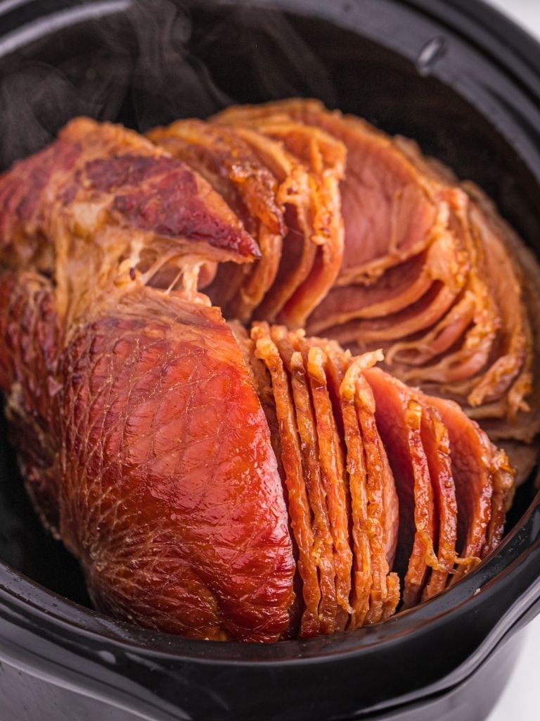 Slow cooker insert with a spiral cut ham inside of it. 
