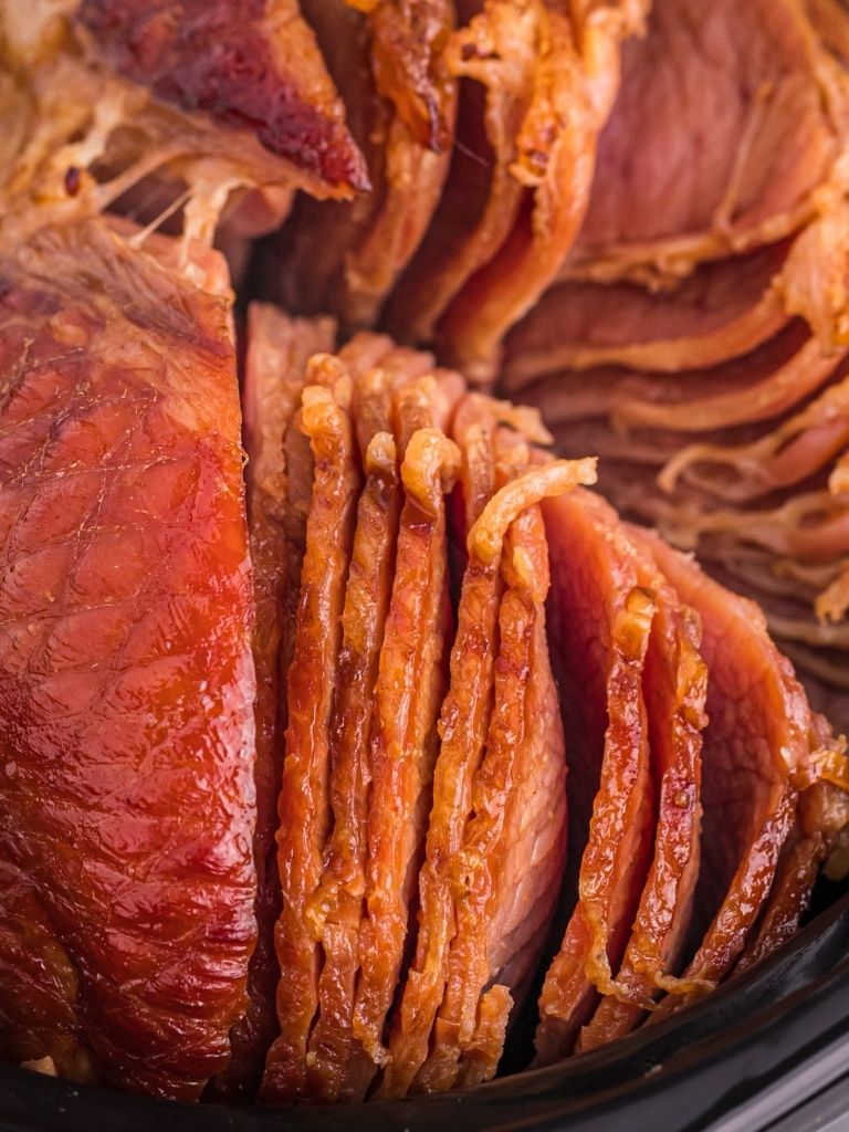 Spiral ham with a brown sugar glaze inside a crock pot with the spirals showing. 