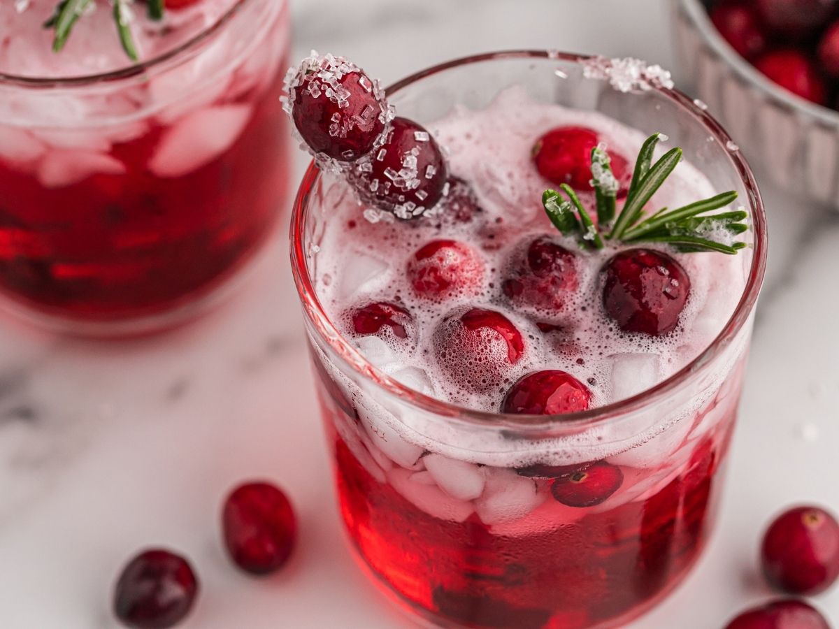 Glass cups of cranberry punch recipe topped with fresh cranberries. 