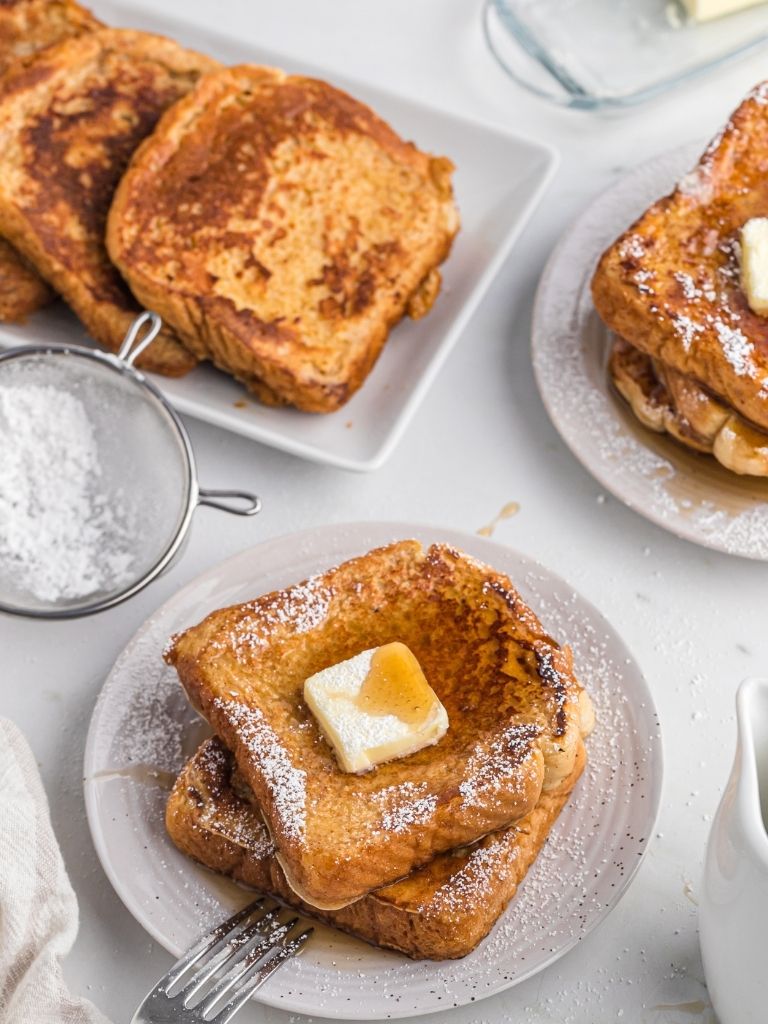 Overhead shot of a platter of French toast and a plate with a stack of some. 