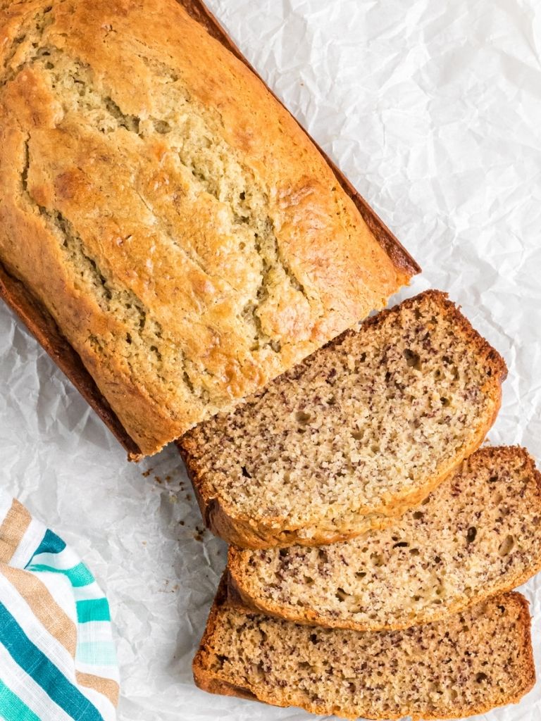 A sliced loaf of quick banana bread recipe with a teal towel next to it. 