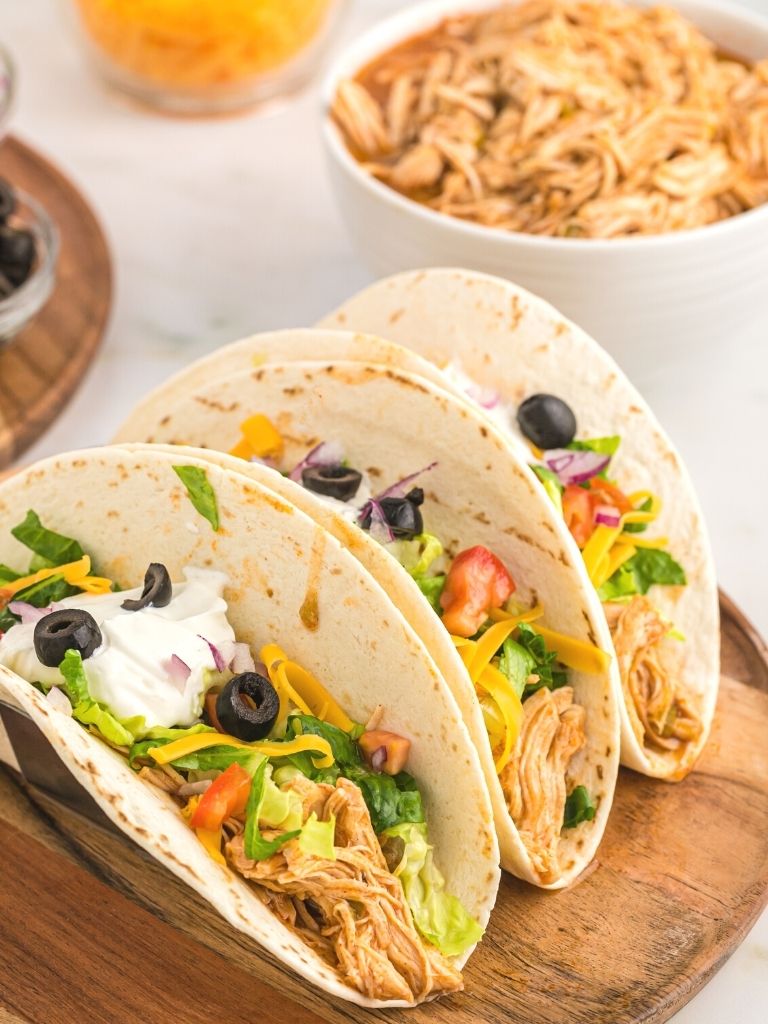 Chicken tacos with toppings in the background on a white background. 