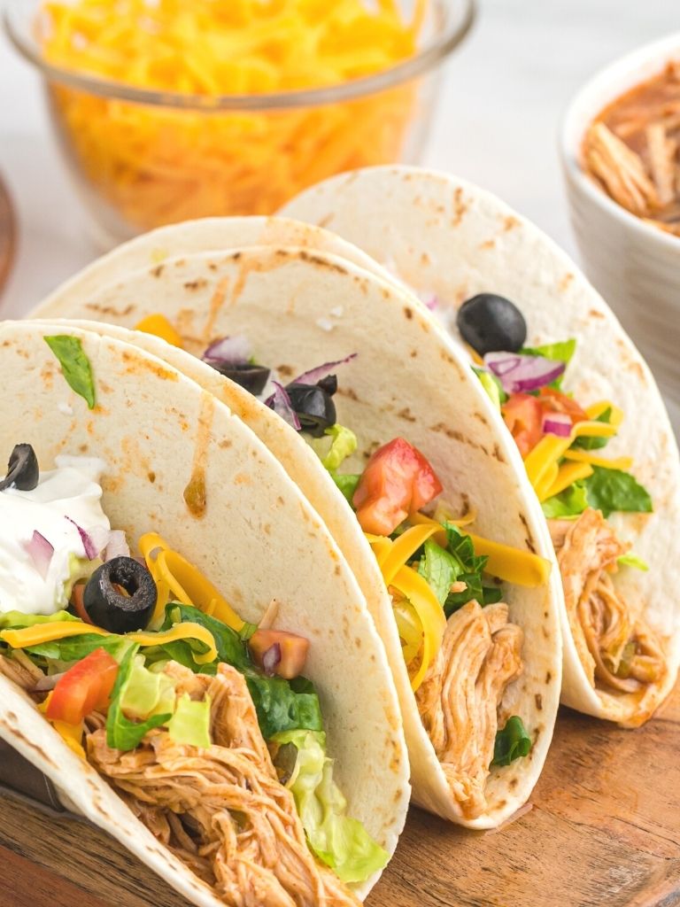 Shredded chicken tacos in flour tortillas with taco toppings. 