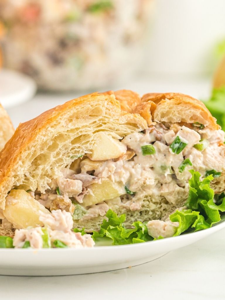 A croissant with chicken salad inside of it cut in half to see the middle. 