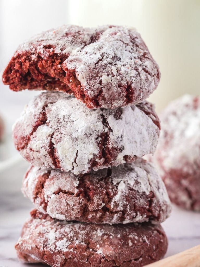 Stack of red velvet cookies with the top cookie with a bite taken out of it to show the center.