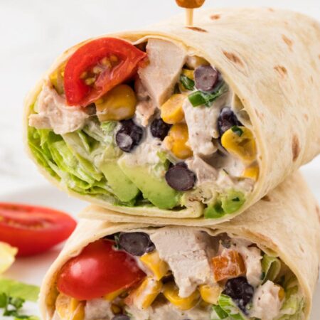 A chicken salad wrap cut in half and stacked on top of each other with a toothpick.