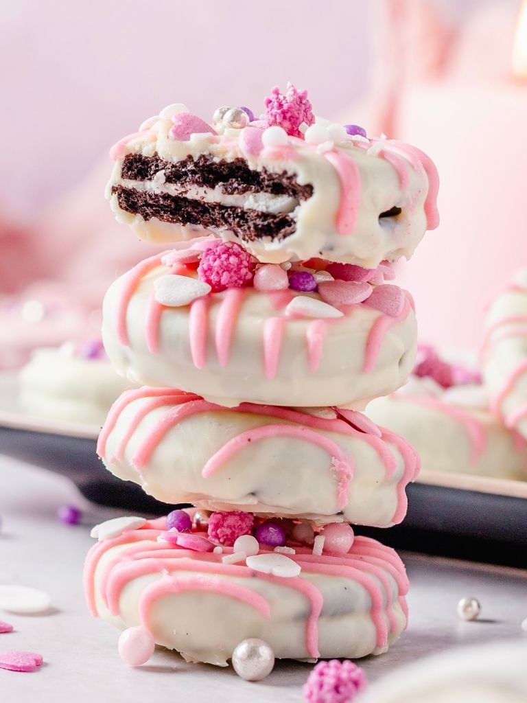 Stack of dipped Oreo cookies with the top one having a bite taken out of it. 