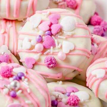 Close up of a decorated Oreo cookie in pink and sprinkles.