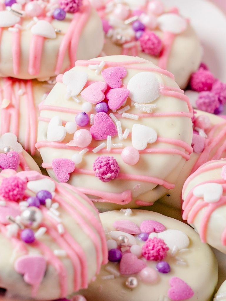Close up of a decorated Oreo cookie in pink and sprinkles. 