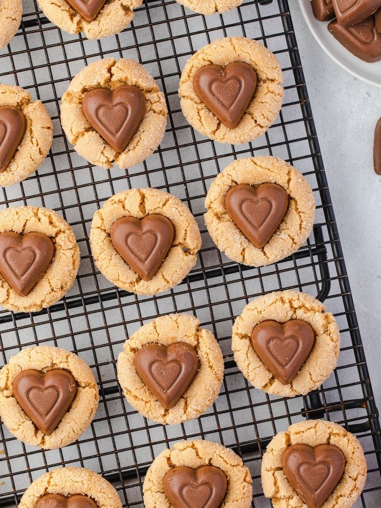 Cooling rack with peanut butter cookies topped with a chocolate heart.