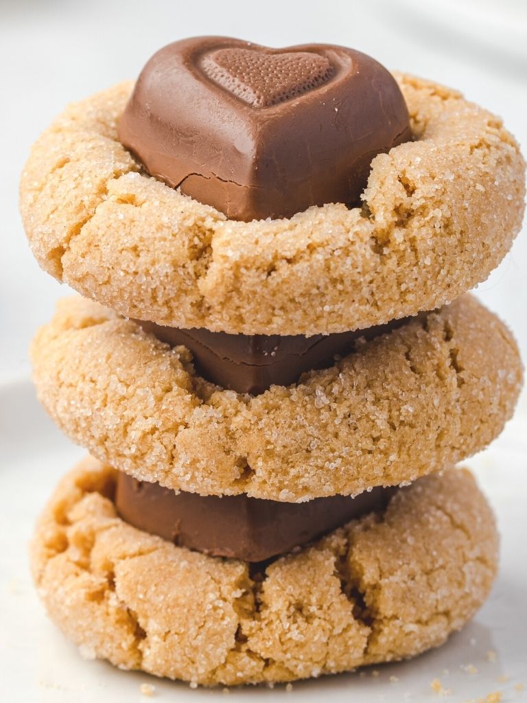 Stack of three cookies with a heart chocolate on top of each one.
