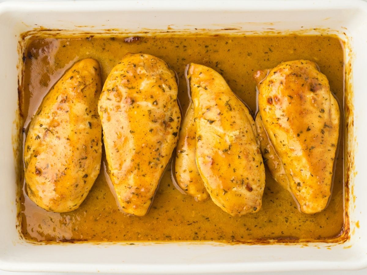 Horizontal photo of chicken inside a baking dish with sauce on it. 