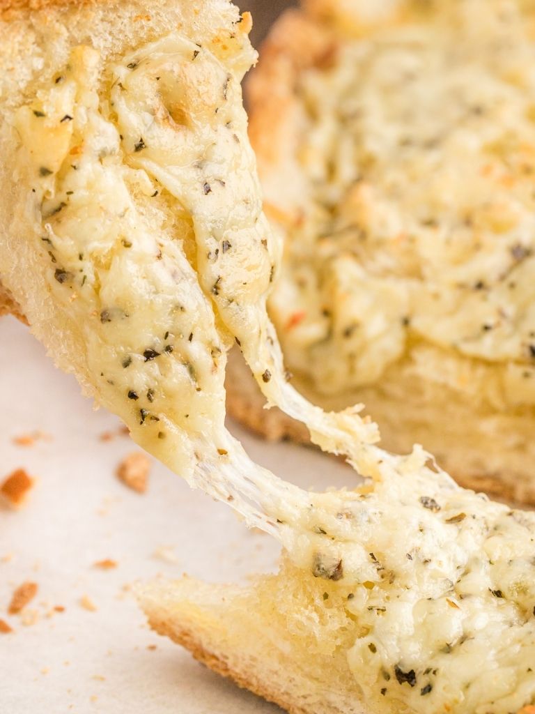 A picture of garlic bread being pulled apart with the cheese pull. 