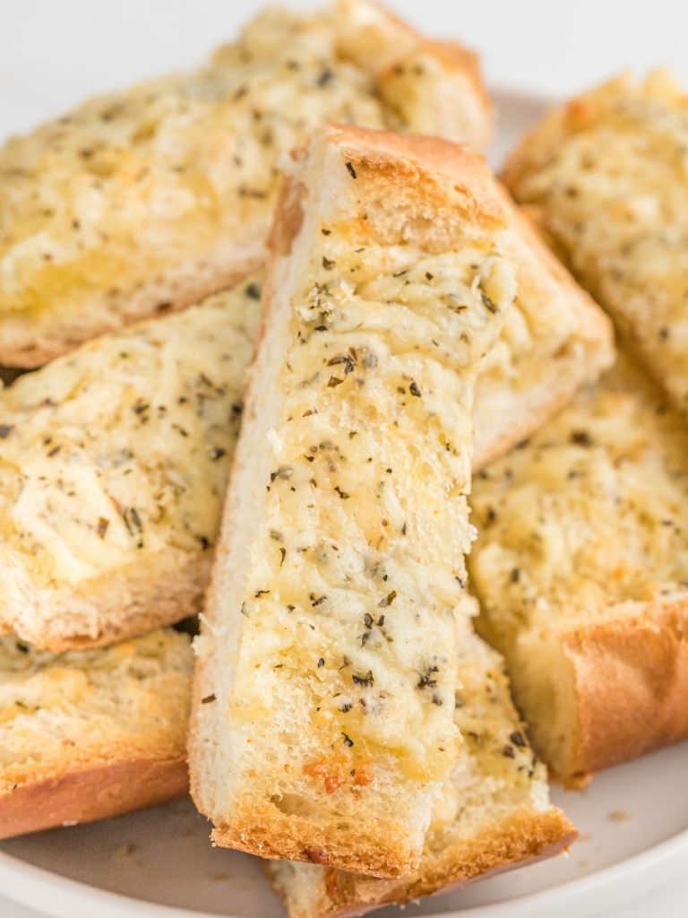A pile of garlic bread on a white plate