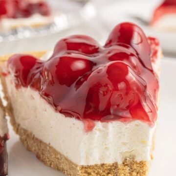 A slice of pie on a white plate topped with cherry filling.