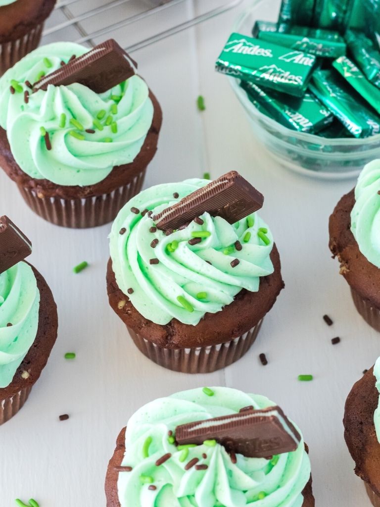 cupcakes on a white background with frosting and a mint on top of each one. 