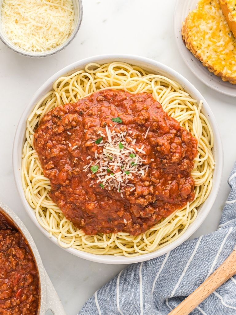 Overhead shot of a bowl of noodles with sauce on top and parmesan cheese. 